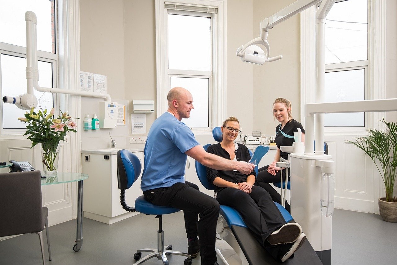 Dental practice exam room with a clinician and patient reviewing care details.